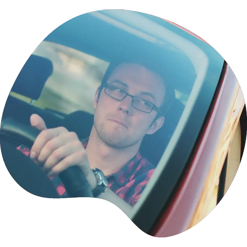 Man with glasses driving a red car